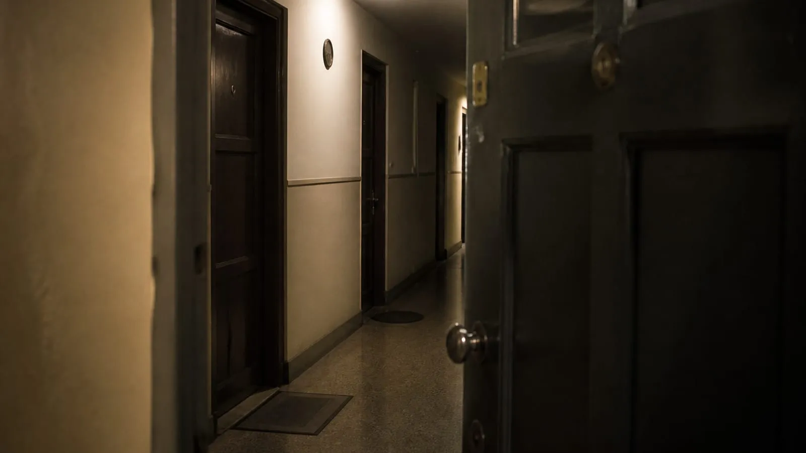 Corredor de apartamentos à noite, com portas fechadas e luz baixa