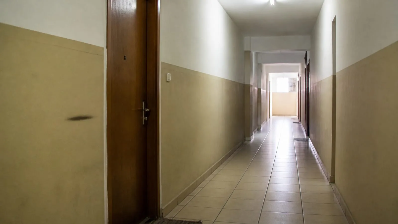 Corredor de apartamentos com uma porta fechada, tapete e parede bege